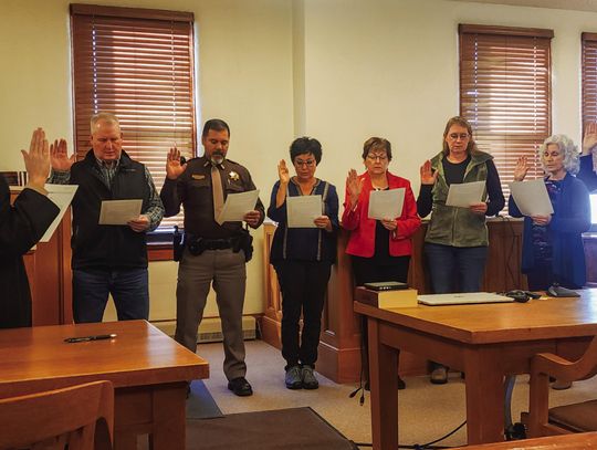 District Court Judge Andrea Miller, left, recites the oath of office with County Commissioner Jeff Metz, Sheriff Milo Cardenas, Commissioner Susanna Batterman, County Clerk Kathy Brandt, County Assessor Rose Nelson, County Treasurer Loretta McCoy, and County Attorney Kirk Fellhoelter durin...