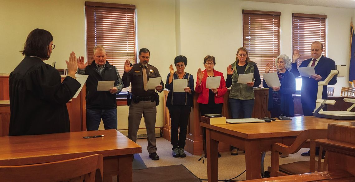 District Court Judge Andrea Miller, left, recites the oath of office with County Commissioner Jeff Metz, Sheriff Milo Cardenas, Commissioner Susanna Batterman, County Clerk Kathy Brandt, County Assessor Rose Nelson, County Treasurer Loretta McCoy, and County Attorney Kirk Fellhoelter durin...